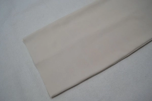 Gros plan du tissu de la robe bandage beige montrant la maille fine et la matière douce