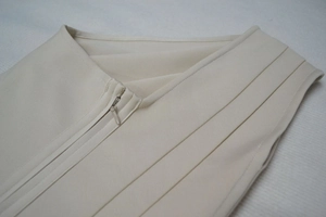 Détail de la fermeture éclair invisible et du tissu sergé sur une robe bandage beige