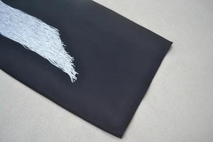 Détail du tissu bandage noir avec franges argentées denses et reflets métalliques