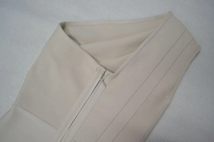 Détail du tissu beige de la robe bandage avec fermeture éclair invisible et texture côtelée