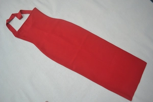 Dettaglio di un grembiule rosso con scollo a la halter in tessuto di saia e cuciture