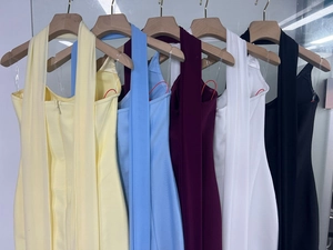 Detail view of colorful halter neck bodycon dresses hanging on wooden hangers in five shades