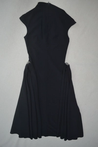 Détail de robe noire sans manches à col montant avec anneaux métalliques à la taille