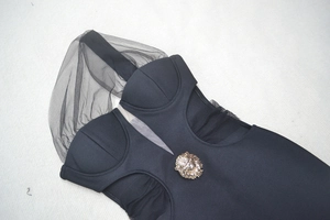Detail of V-neck bandage dress with golden lion head emblem and mesh stitching