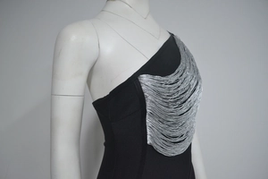 Détail de la robe bandage noire asymétrique avec des franges argentées brillantes