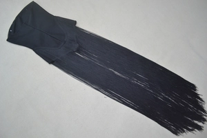 Detailed view of black corset dress with long fringe hem and bandage fabric texture