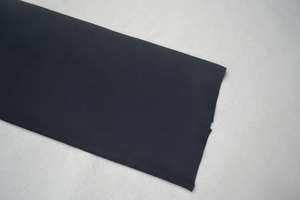Close-up detail of smooth black woven fabric and neat hemline stitching on this dress