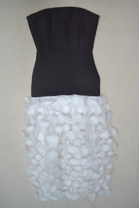 Detail of 3D white floral petals on the hem of a black strapless party evening dress