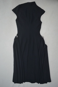 Détail d'une boucle métallique sur une robe de soirée noire sans manches à taille plissée