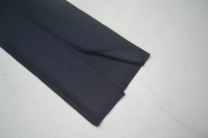 Detail view of the black slim-fit dress featuring a high-quality slit hem and precise stitching
