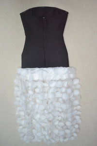 Detail of black strapless bodice with white 3D floral organza skirt on beige fabric