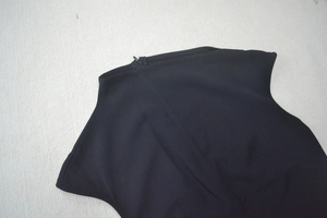 Détail de la fermeture éclair invisible et du col montant sur robe noire sans manches
