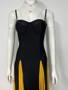 Detail view of black bandage dress showing fine fabric texture and yellow pleated hem contrast