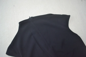 Détail du col asymétrique avec fermeture éclair invisible sur robe de soirée noire