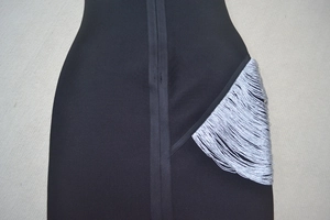 Gros plan sur une robe bandage noire ornée de franges argentées à l'éclat métallique