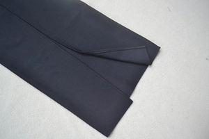 Close-up of black sleeveless bandage dress showing refined hem slit and premium twill fabric