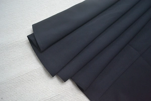 Vue détaillée du tissu plissé noir montrant le plissage régulier de la robe de soirée