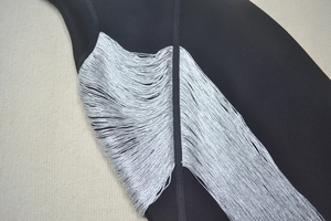 Détail de franges argentées sur une robe bandage noire avec coutures de haute qualité