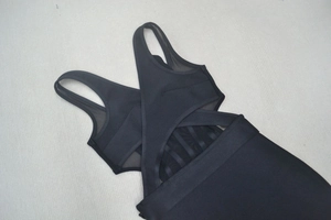 Détail de robe bandage noire avec bretelles croisées et empiècements en maille filet