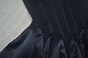 Détails des coutures noires contrastées sur le tissu côtelé et le satin de la robe