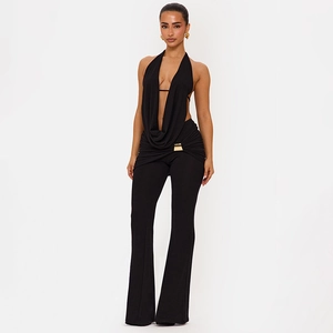 Detail von schwarzem Neckholder-Top und Schlaghose mit goldenem Schnallendekor