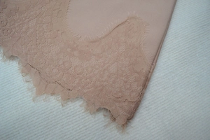 Détail de la robe bandage chair avec bordure en dentelle florale et tissu extensible lisse