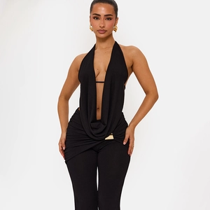 Detail eines eleganten schwarzen Neckholder-Tops und Hose mit goldener Schnalle