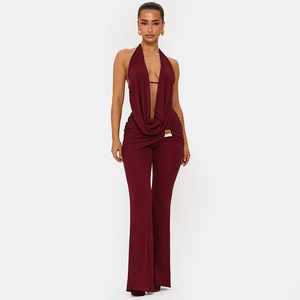 Detail eines burgunderroten Neckholder Jumpsuits mit tiefem V-Ausschnitt und Goldpaspel
