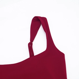 Gros plan de la large bretelle torsadée sur un corsage de robe rouge foncé
