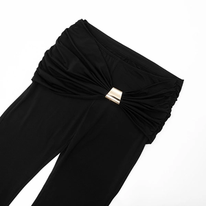 Detail einer eleganten schwarzen Schlaghose mit drapiertem Bund und goldener Metallschnalle