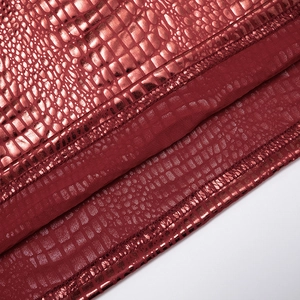 Dettaglio macro del tessuto rosso scuro metallizzato con trama a serpente e cuciture