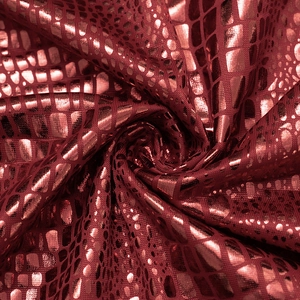 Dettaglio macro del tessuto a scaglie metalliche rosso scuro con trama a pelle di serpente