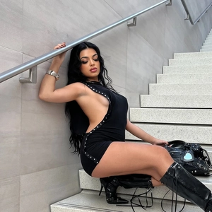 Detail of black mini dress with metal eyelet cut-outs and stylish knee-high leather boots