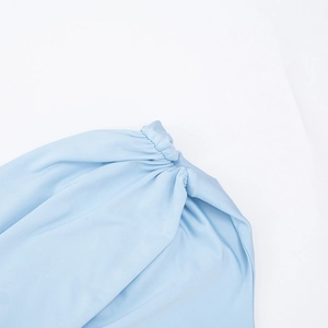 Gros plan détaillé du nœud torsadé en tissu bleu clair et texture plissée de la robe