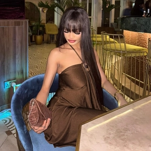 Detail of elegant brown satin halter mini dress paired with a crocodile texture clutch