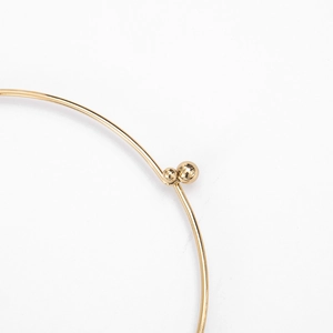 Makroaufnahme eines polierten goldenen Metallrings mit zwei Kugeln und glänzendem Finish