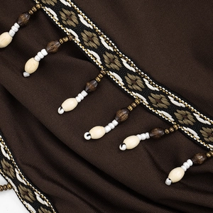 Detailansicht des Boho-Halterkleids mit braunem Rippstoff und Perlenfransenbesatz