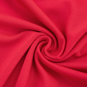 Macro texture de maille côtelée rouge pliée en spirale montrant l'épaisseur du matériau
