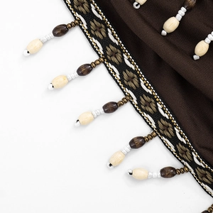 Detailansicht eines Boho-Kleides mit braunem Rippstoff und Perlenfransen-Verzierung