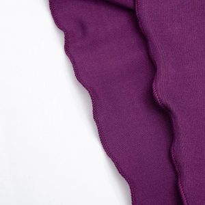 Detail of purple knit fabric featuring elegant ruffled hem and fine stitching