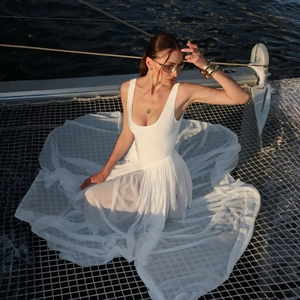 Detail of white two-piece swimsuit and sheer mesh maxi skirt on a yacht deck