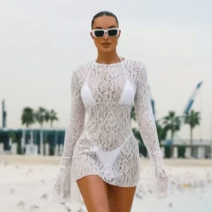 Close-up of white floral lace fabric and flared sleeves on a beach cover-up dress