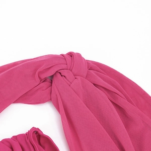 Détail de la robe en maille rose rouge avec design noué et tissu texturé transparent