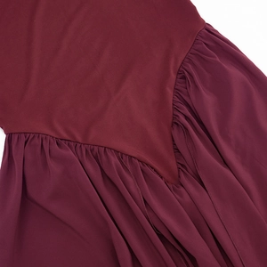 Detail of burgundy dress showing seamless stitching between smooth fabric and pleated chiffon