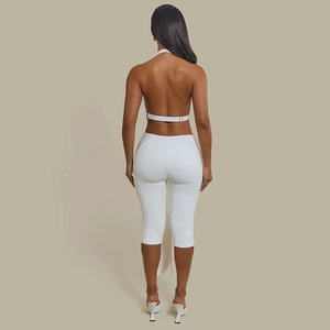 Detail of a white halter backless top and trousers set showing long side ribbon accents