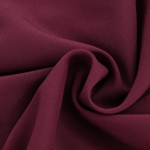 Detailed macro view of the deep burgundy chiffon fabric texture and pleated drape of the dress