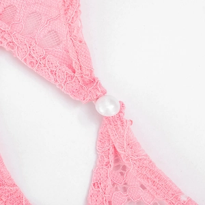 Detail of pink floral lace fabric with a decorative white pearl bead on summer beachwear