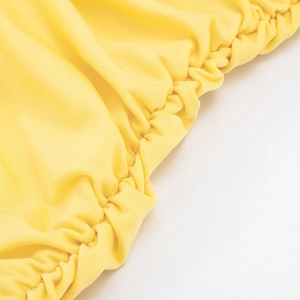 Macro shot of bright yellow ribbed fabric showing elasticated ruched texture detail