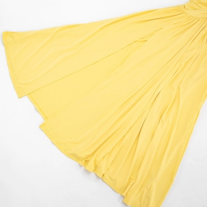Detailed view of the yellow long dress hem with elegant pleats and smooth fabric texture