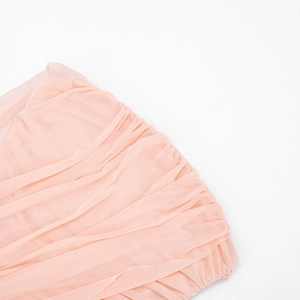 Close-up of pink ruched mesh fabric texture on an elegant sleeveless mini dress